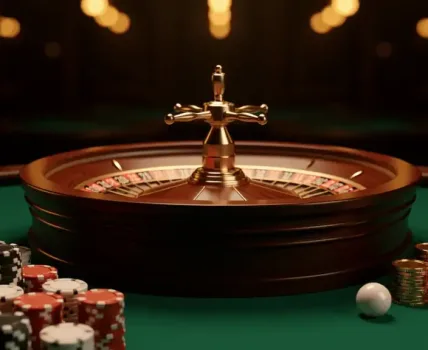 A roulette wheel with chips and coins on a green casino table