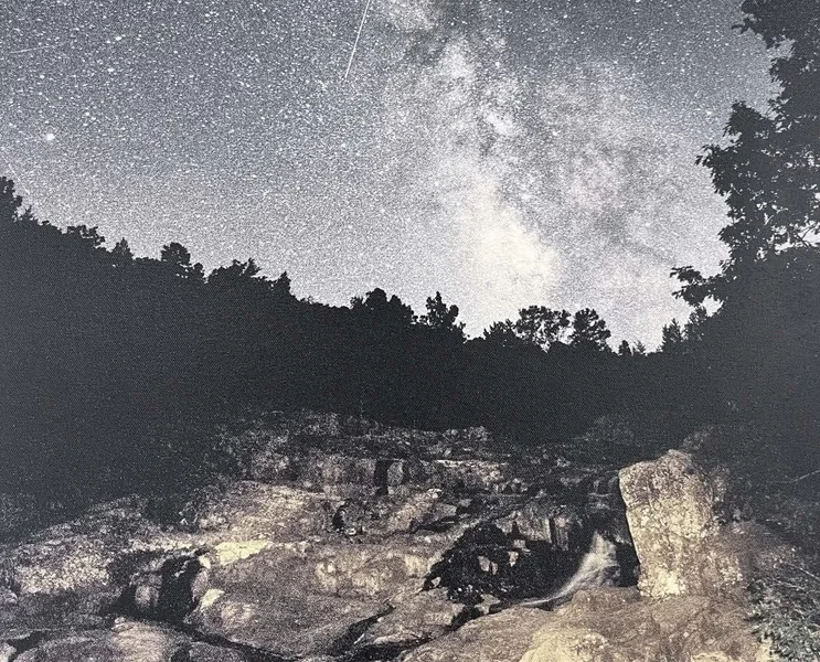 Night sky filled with stars over a rocky landscape